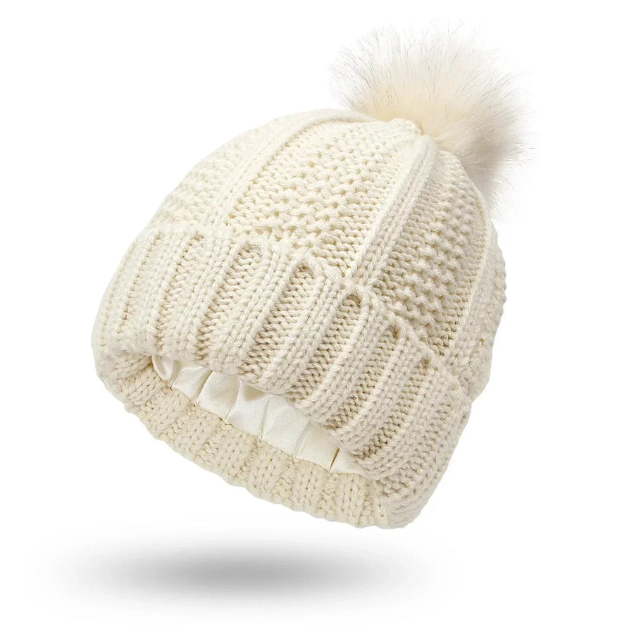 Stickad mössa med fuskpälsboll och satinliknande foder