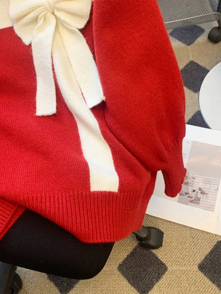 Röd stickad tröja med vitt band och rosett